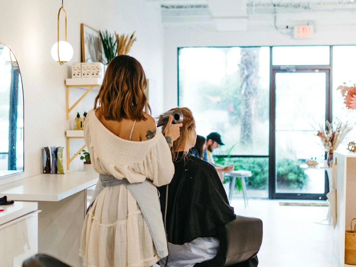 Coiffeuse au travail devant le miroir du salon
