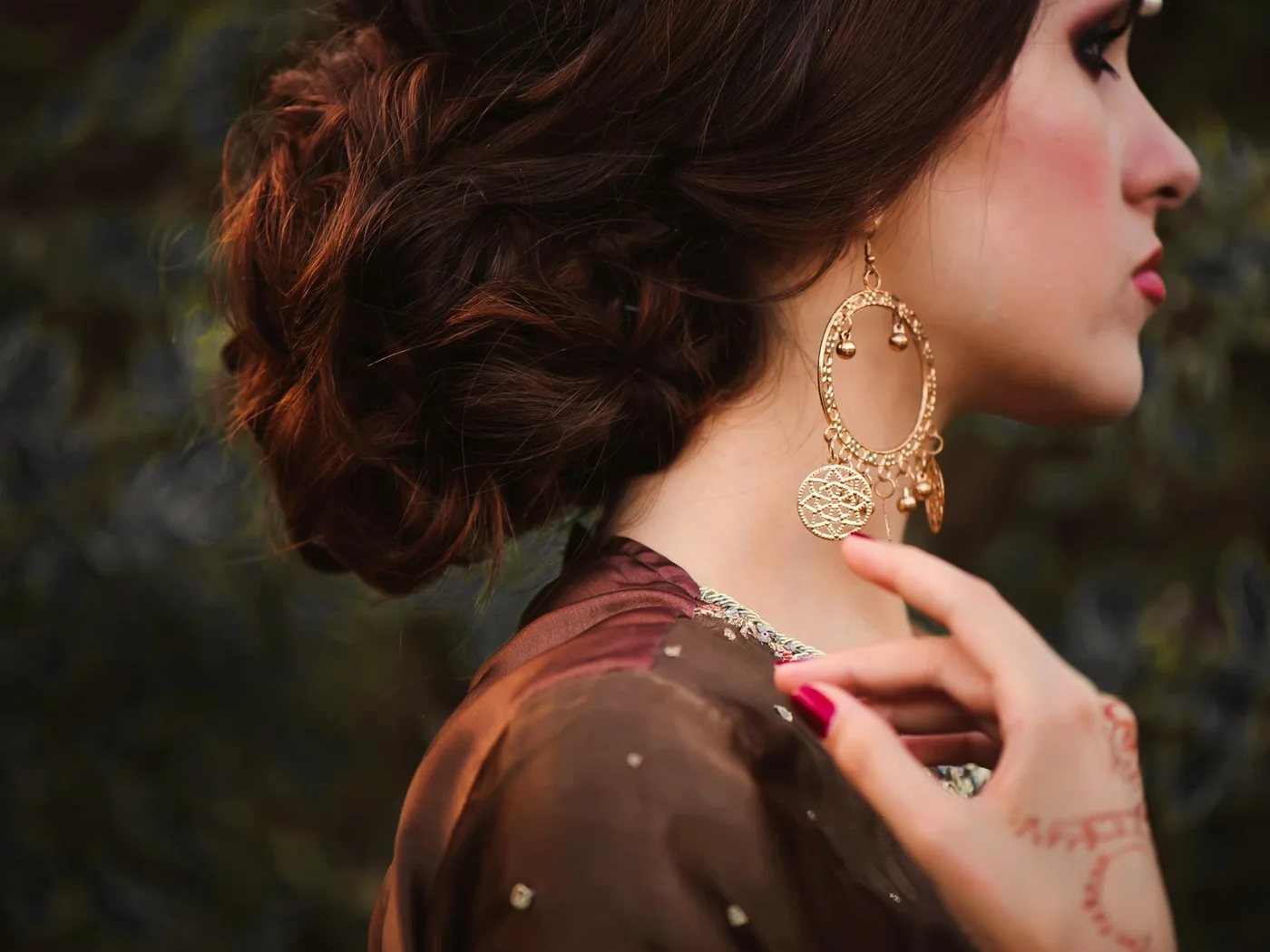 Chignon de mariée, boucle d'oreille en or et henné sur la main